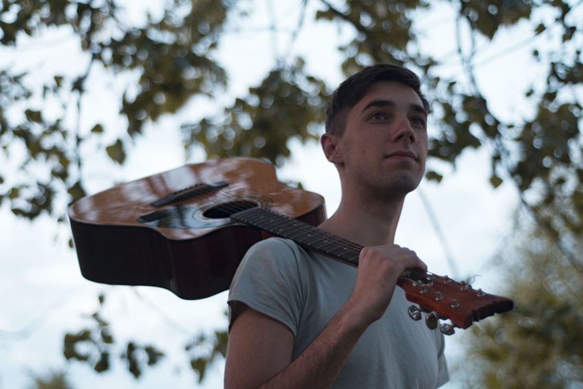 Man plays on acoustic guitar in a park example image 1