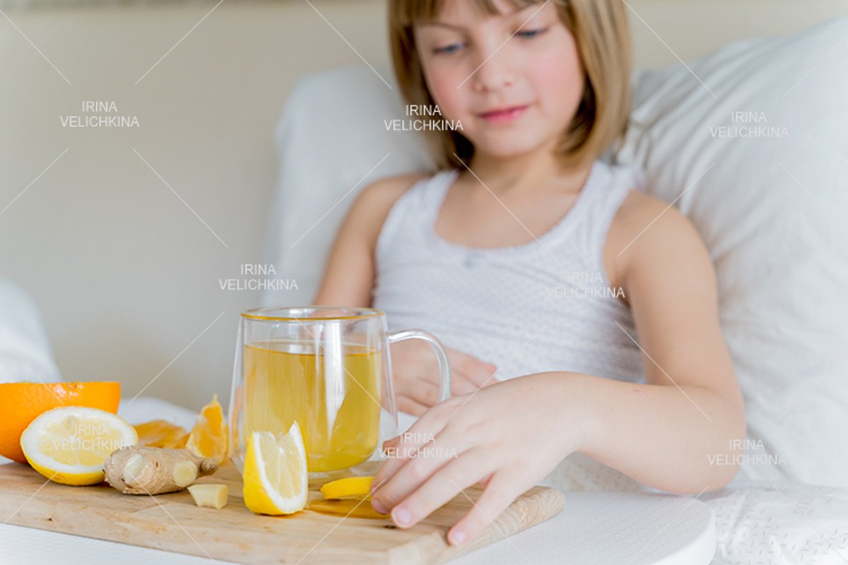 Sick girl in bed. Cup of flu drugs. Tea, orange,lemon,ginger example image 1