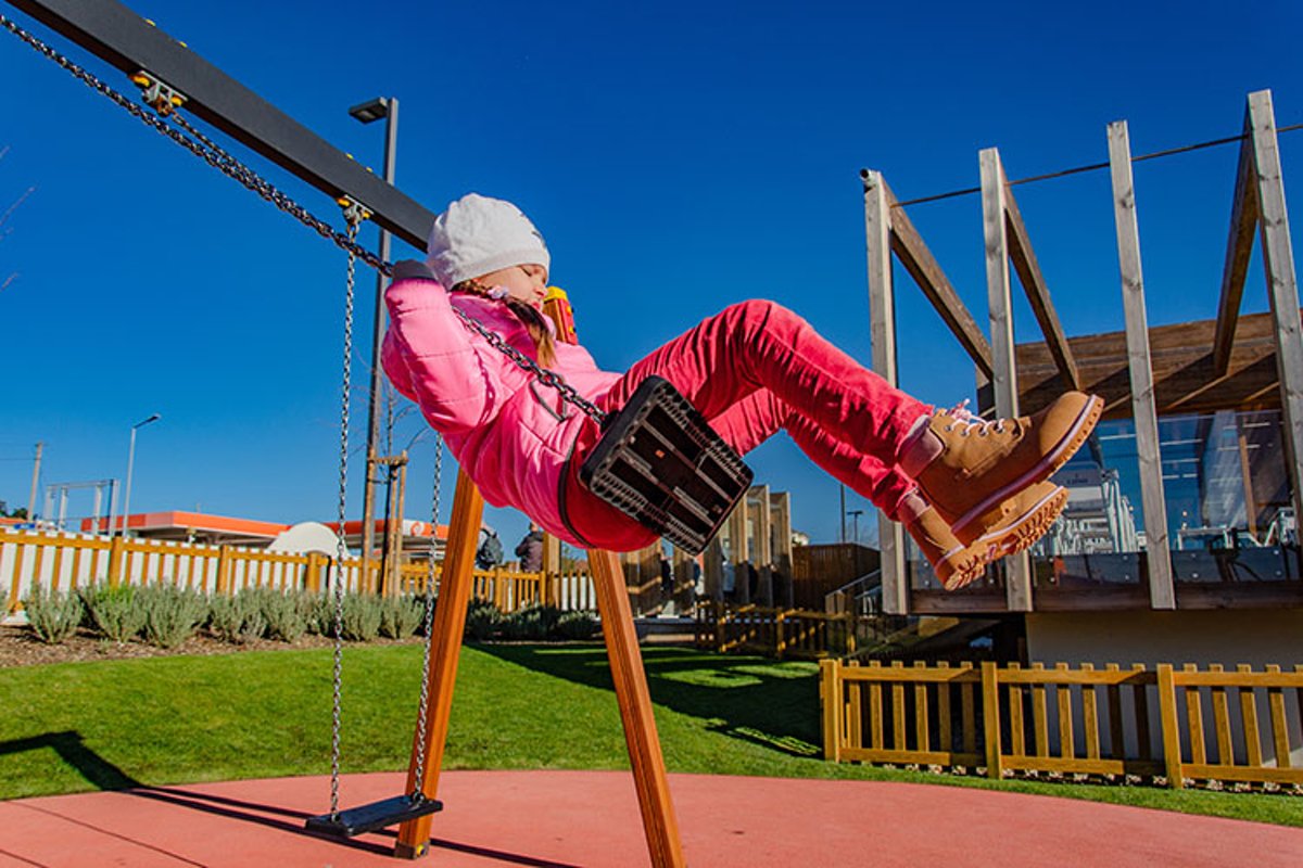 Little girl 5-6 years on a playground swinging on swing. example image 1