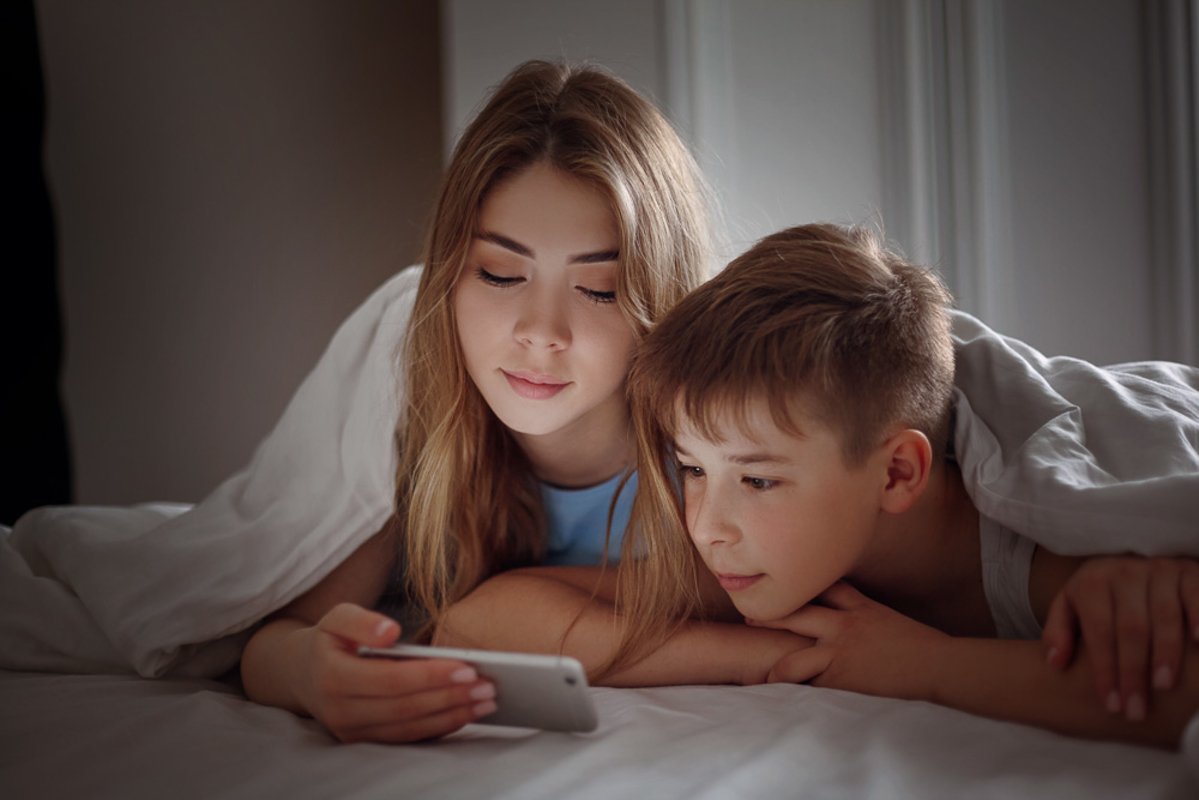 The girl and her younger brother look at photos on the phone example image 1
