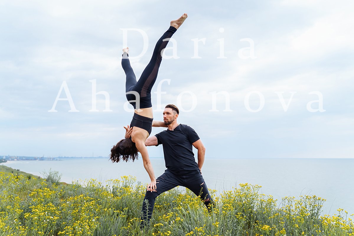 Couple practicing acro yoga poses outdoors outside. example image 1