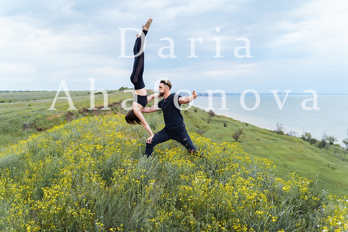 Couple practicing acro yoga poses outdoors outside. example image 1