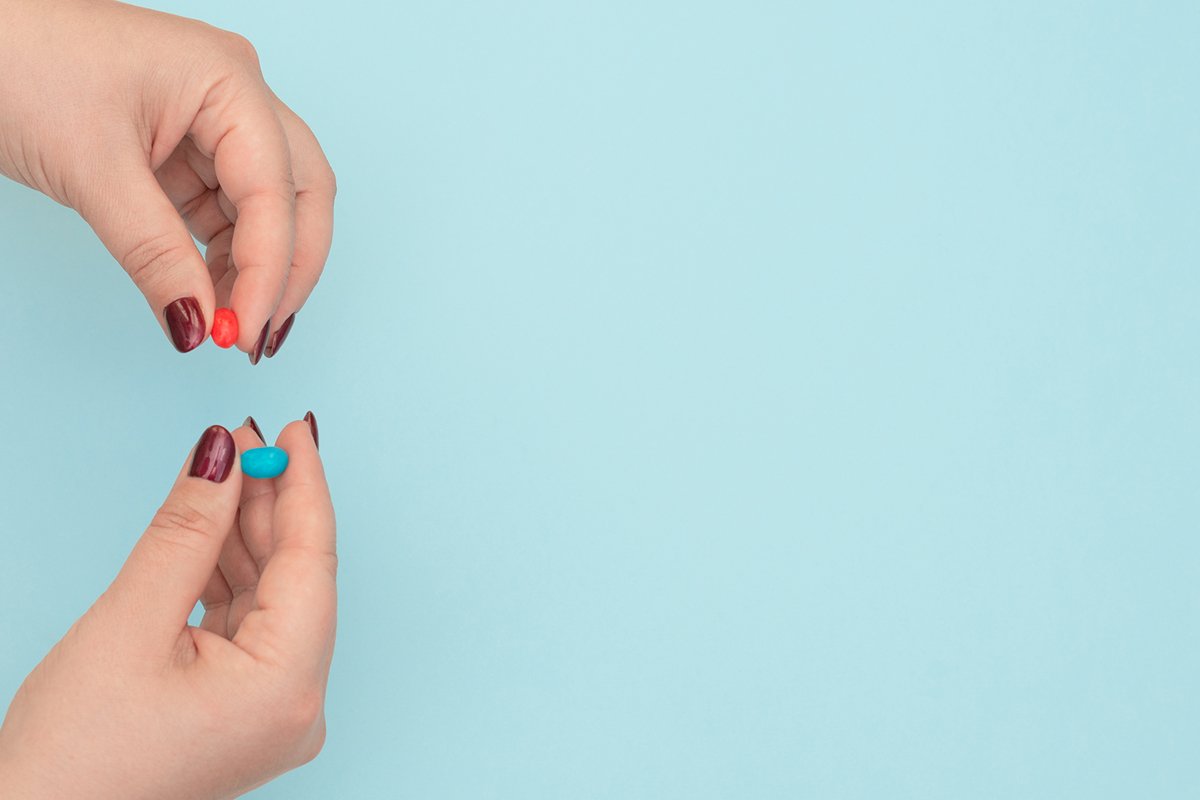 Red and blue pills on female hands on blue background example image 1