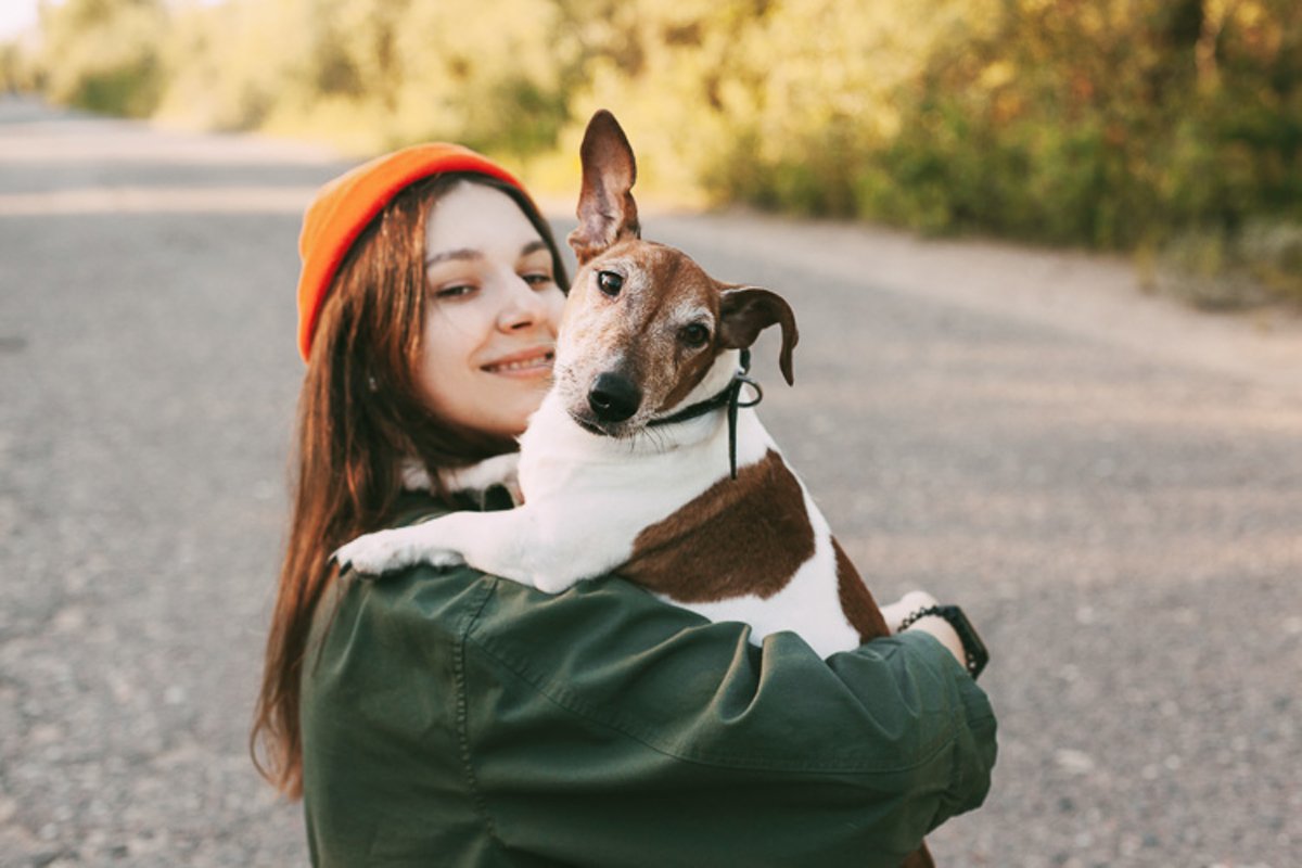 A pretty brunette holds her dog in her arms and smiles. example image 1