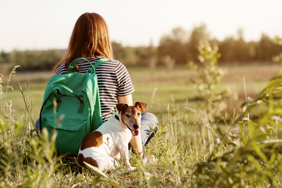 A girl with a green backpack on her back hugs a dog example image 1