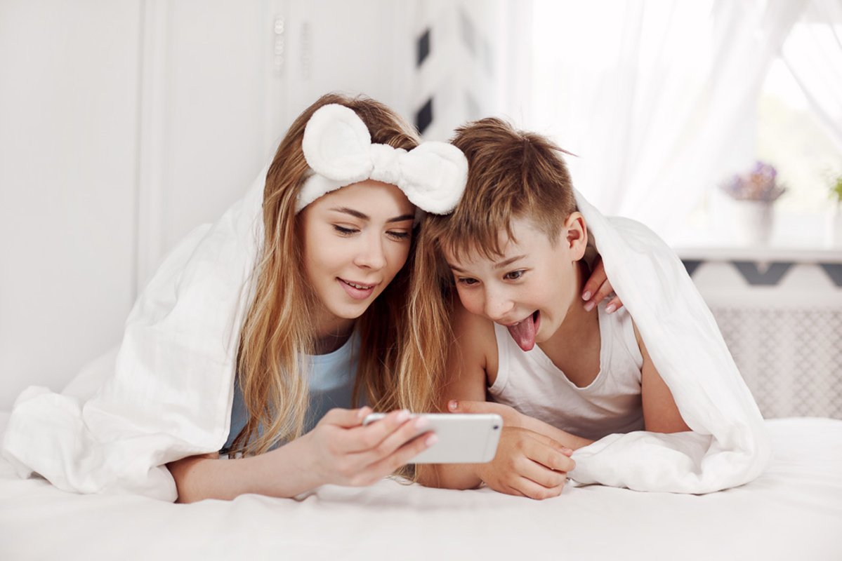 The girl and her younger brother look at photos on the phone example image 1