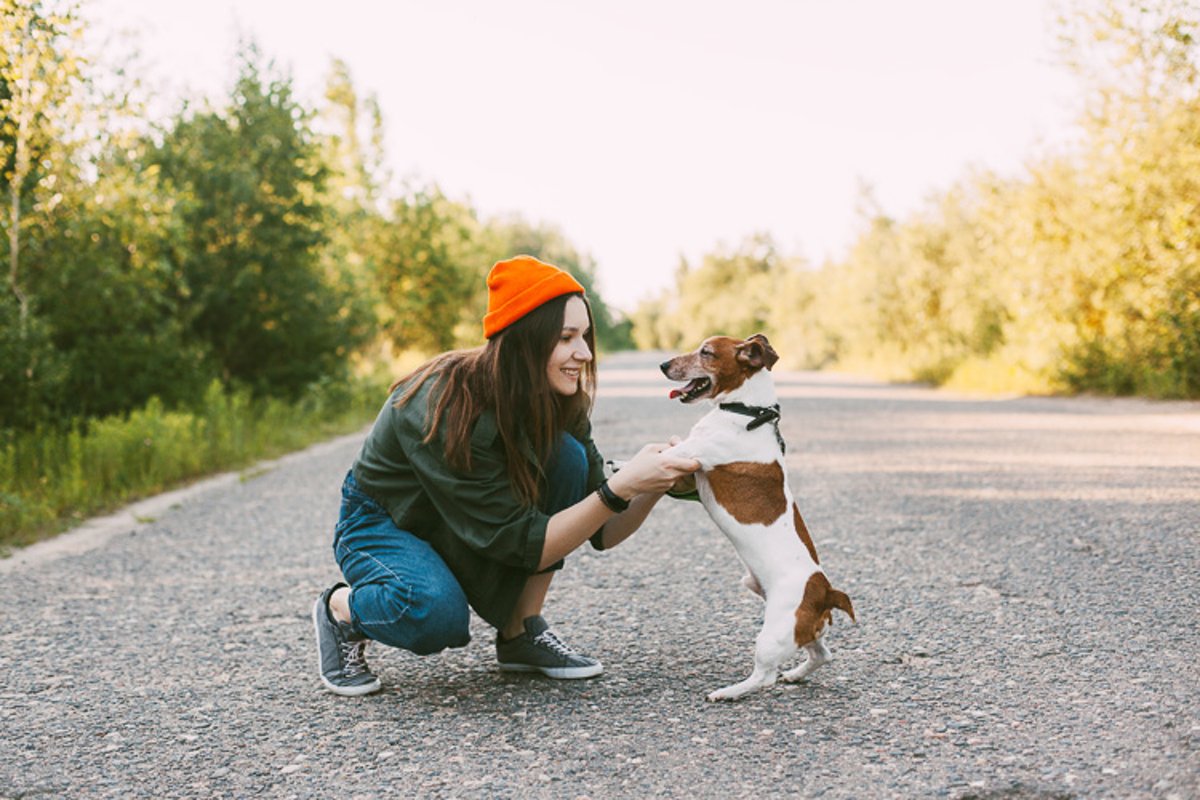 A girl in a green jacket and an orange hat walks with a dog example image 1