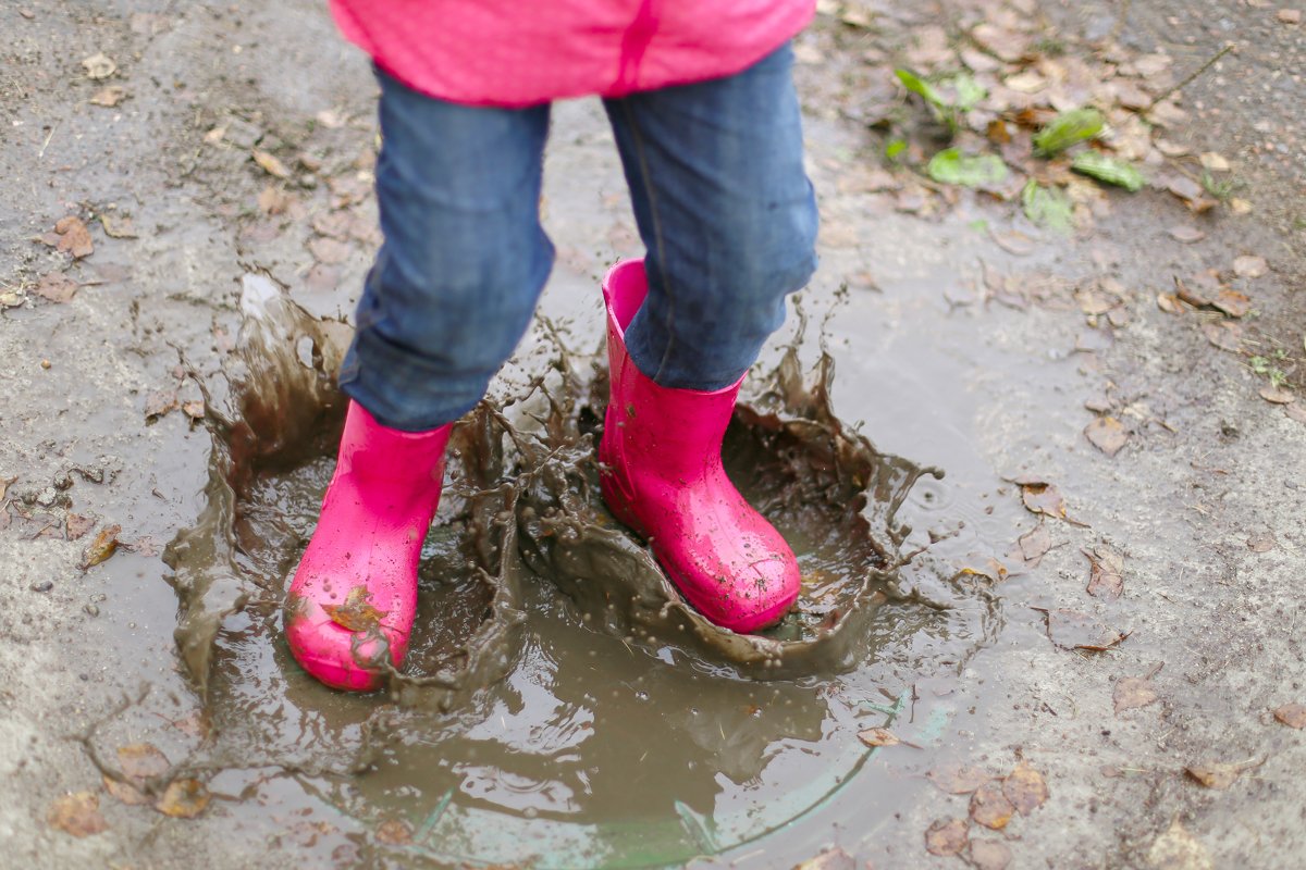 Girl in pink rubber boots jumps through puddle.Spring,autumn example image 1