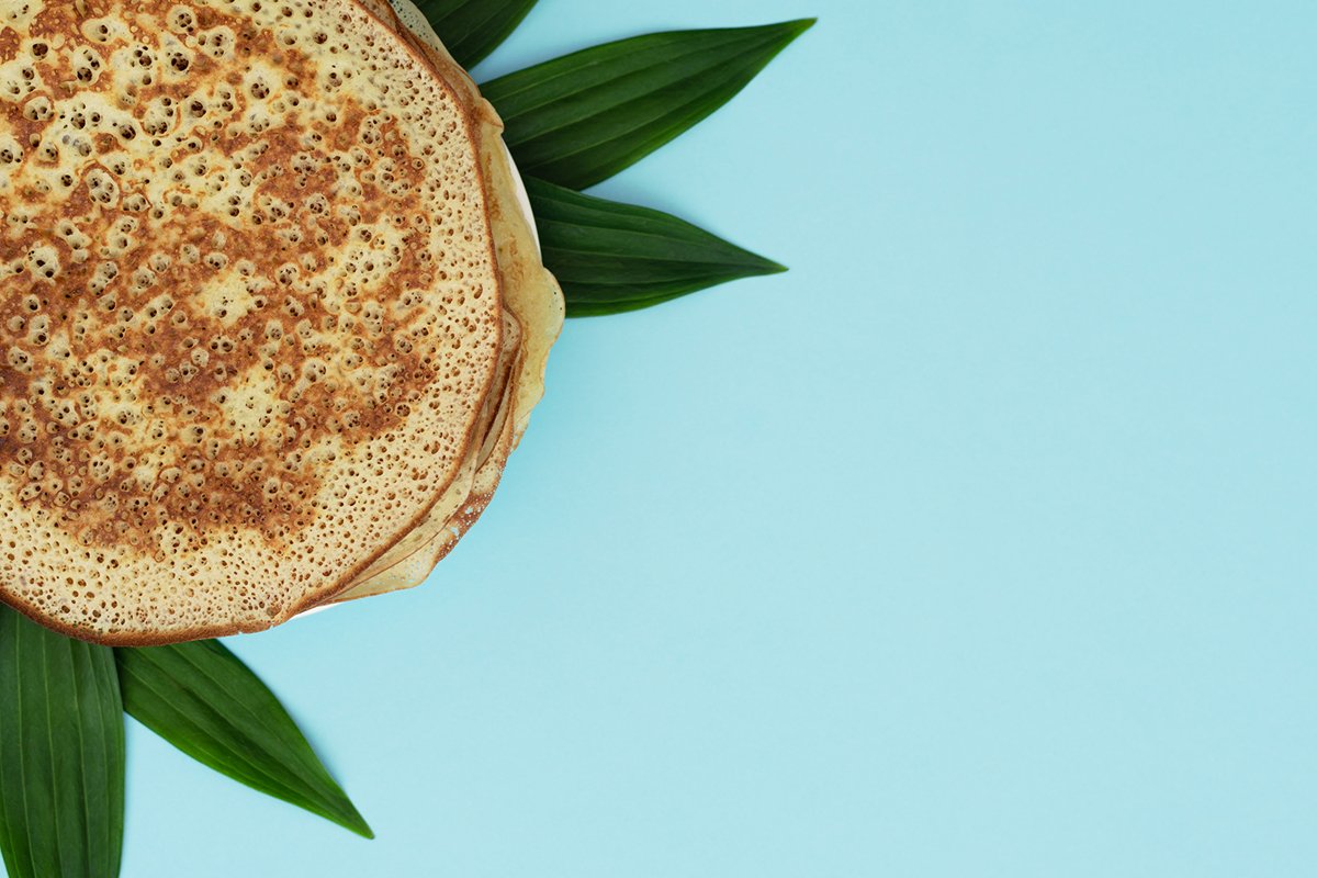 Homemade pancakes on blue background with green leaves example image 1