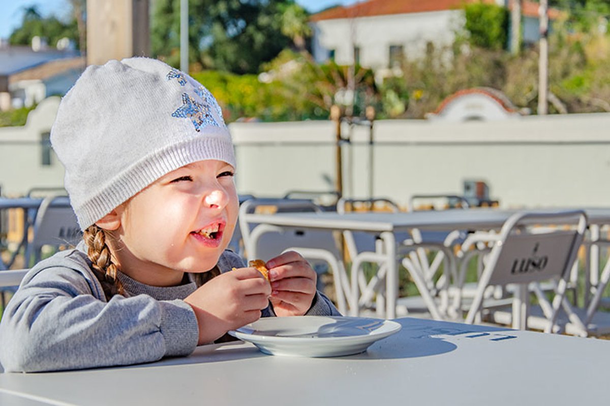 Hungry little girl eating cake in cafe outside example image 1
