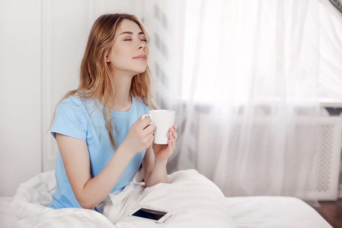 Beautiful girl drinking morning coffee sitting in bed. example image 1