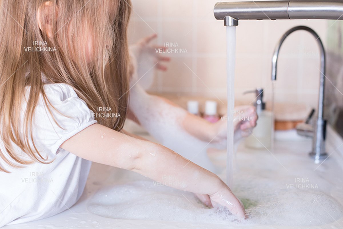 Girls wash their hands in the sink with soap in the foam example image 1