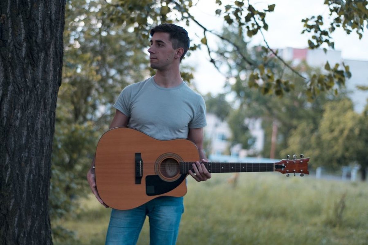 Man plays on acoustic guitar in a park example image 1
