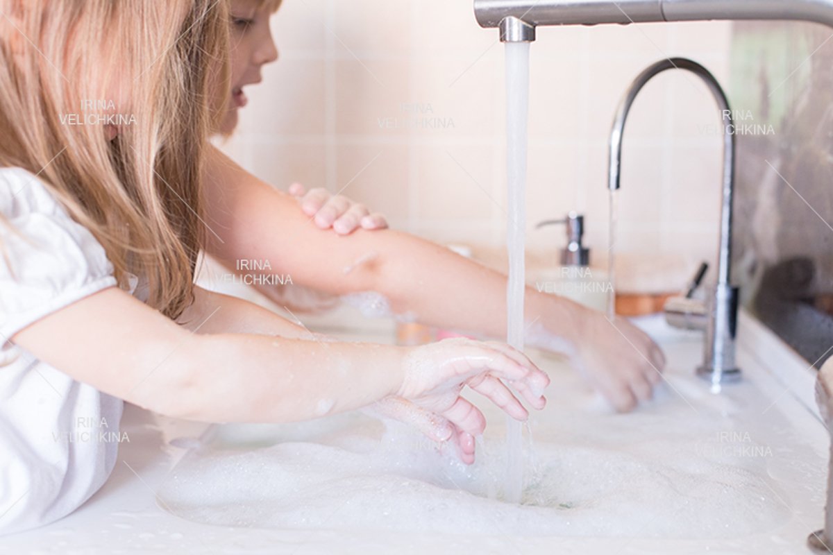 Girls wash their hands in the sink with soap in the foam example image 1