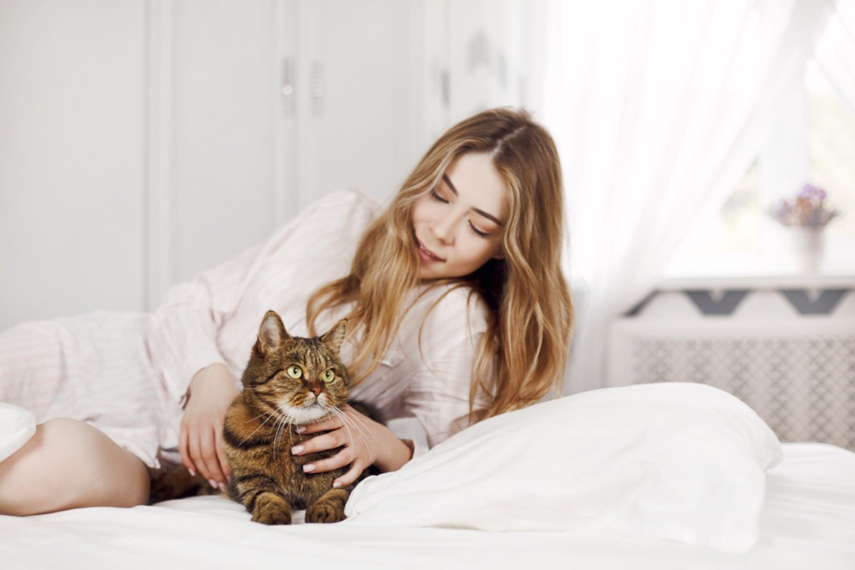 Cute young girl is lying with her cat on the bed at home. example image 1