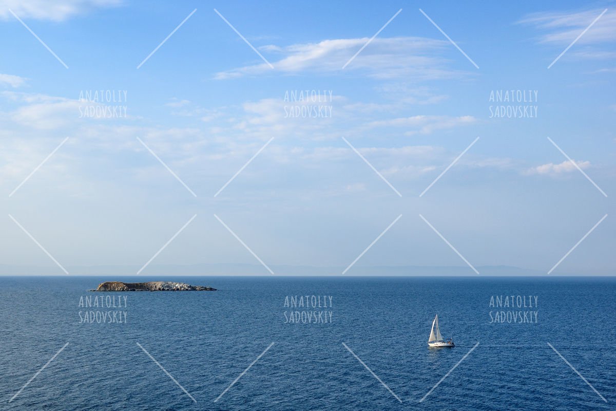 Seascape with sailing yacht and small island in sea example image 1