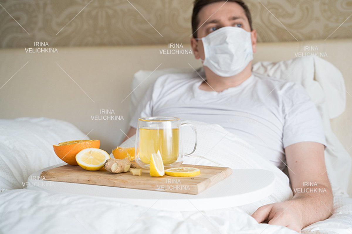Sick man in bed. Face mask. Cup of tea, orange,lemon,ginger example image 1