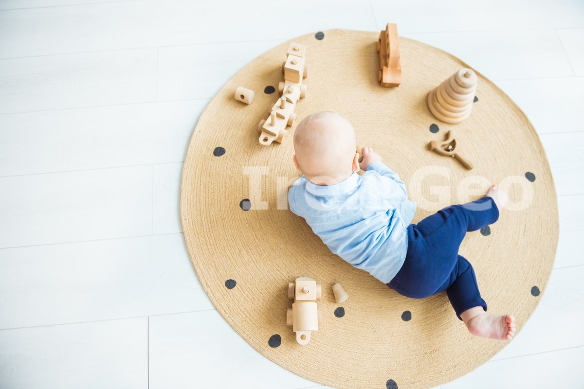 Baby boy playing with wooden toys lying on the Mat example image 1