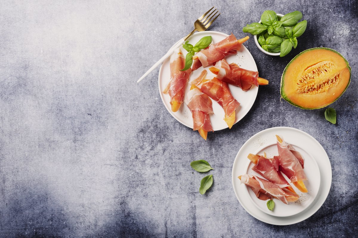 Summer appetizer with sweet melon and ham on dark background example image 1