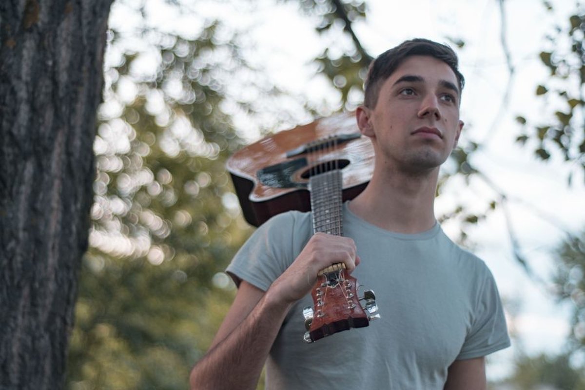 Man plays on acoustic guitar in a park example image 1