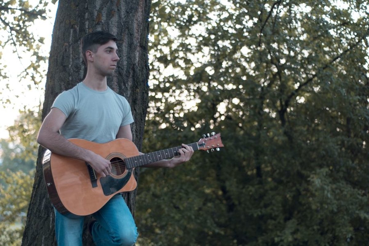 Man plays on acoustic guitar in park example image 1