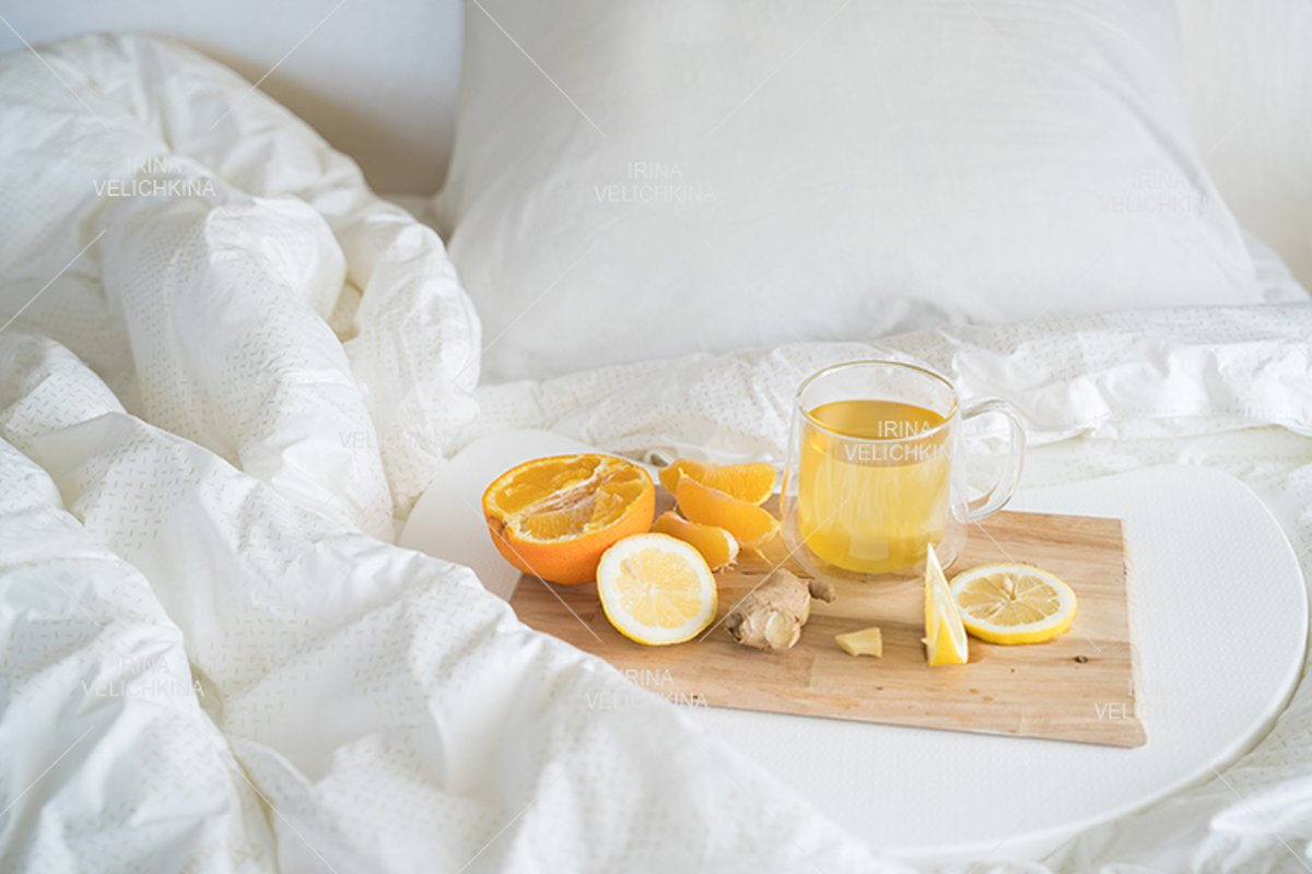 Cup of tea,orange,lemon,ginger in bed.Self treatment for flu example image 1