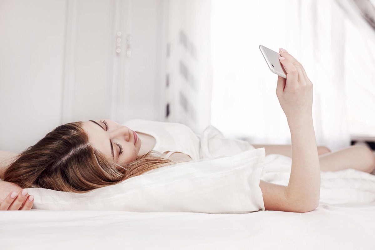 Young girl looks at the phone while lying on the bed example image 1