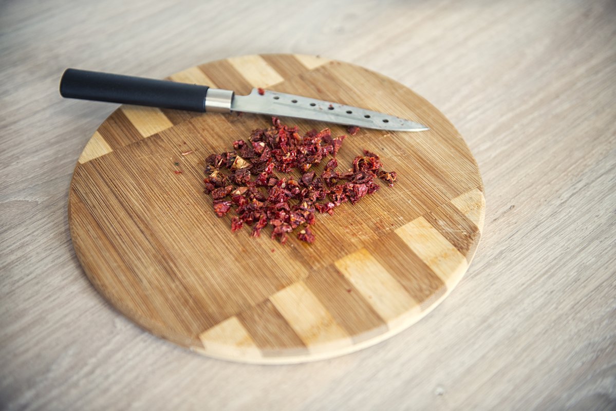 Dry tomatoes finely chopped on a wooden cutting board example image 1