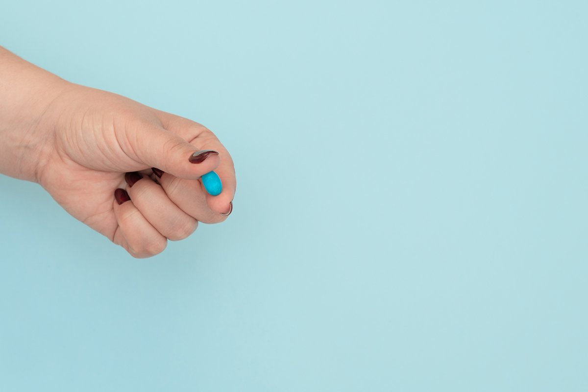 Blue pill on female hand on blue background example image 1