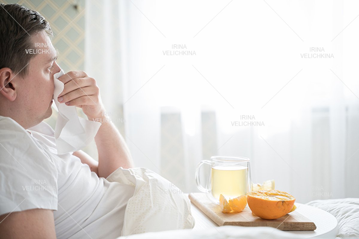Sick man in bed. Cup of flu drugs. Tea, orange,lemon,ginger example image 1