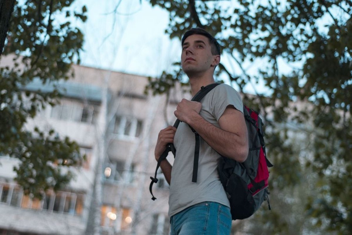 Young caucasian man walks in a park with backpack example image 1