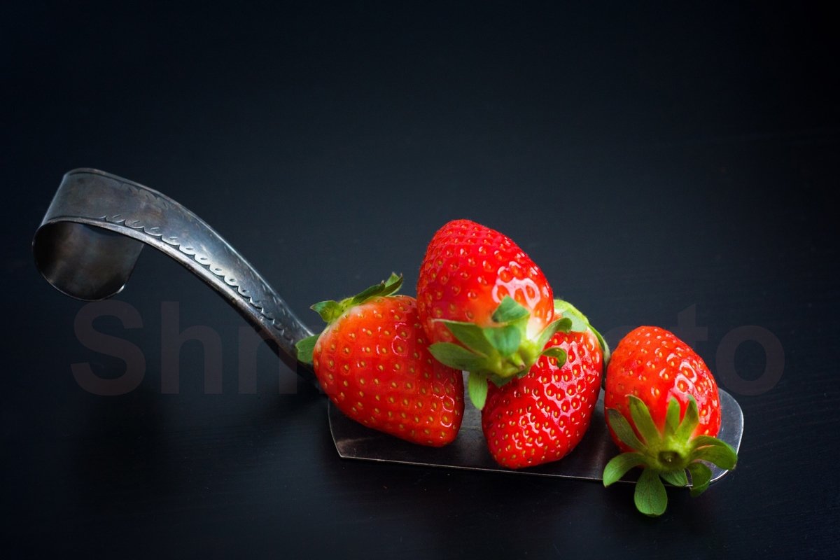 Fresh strawberries at silver spatula on black background example image 1