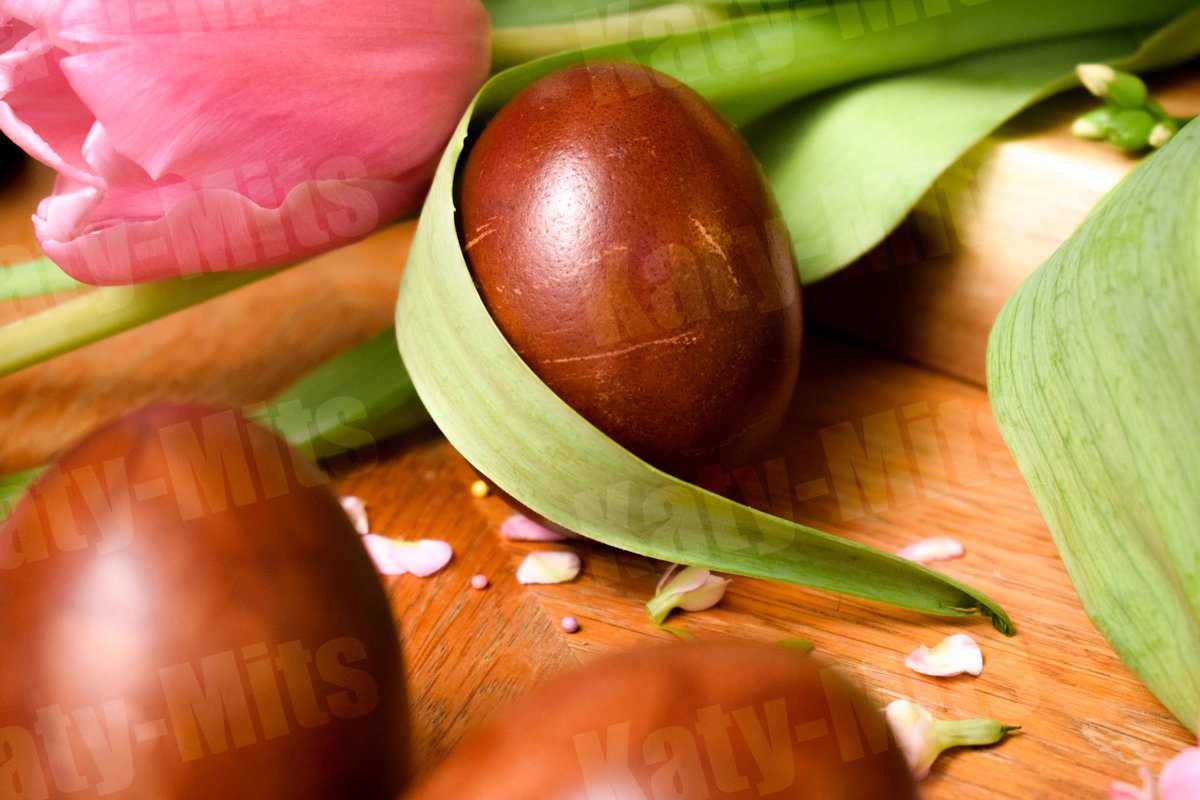 3 Easter eggs on a wooden table with pink flowers and petals example image 1