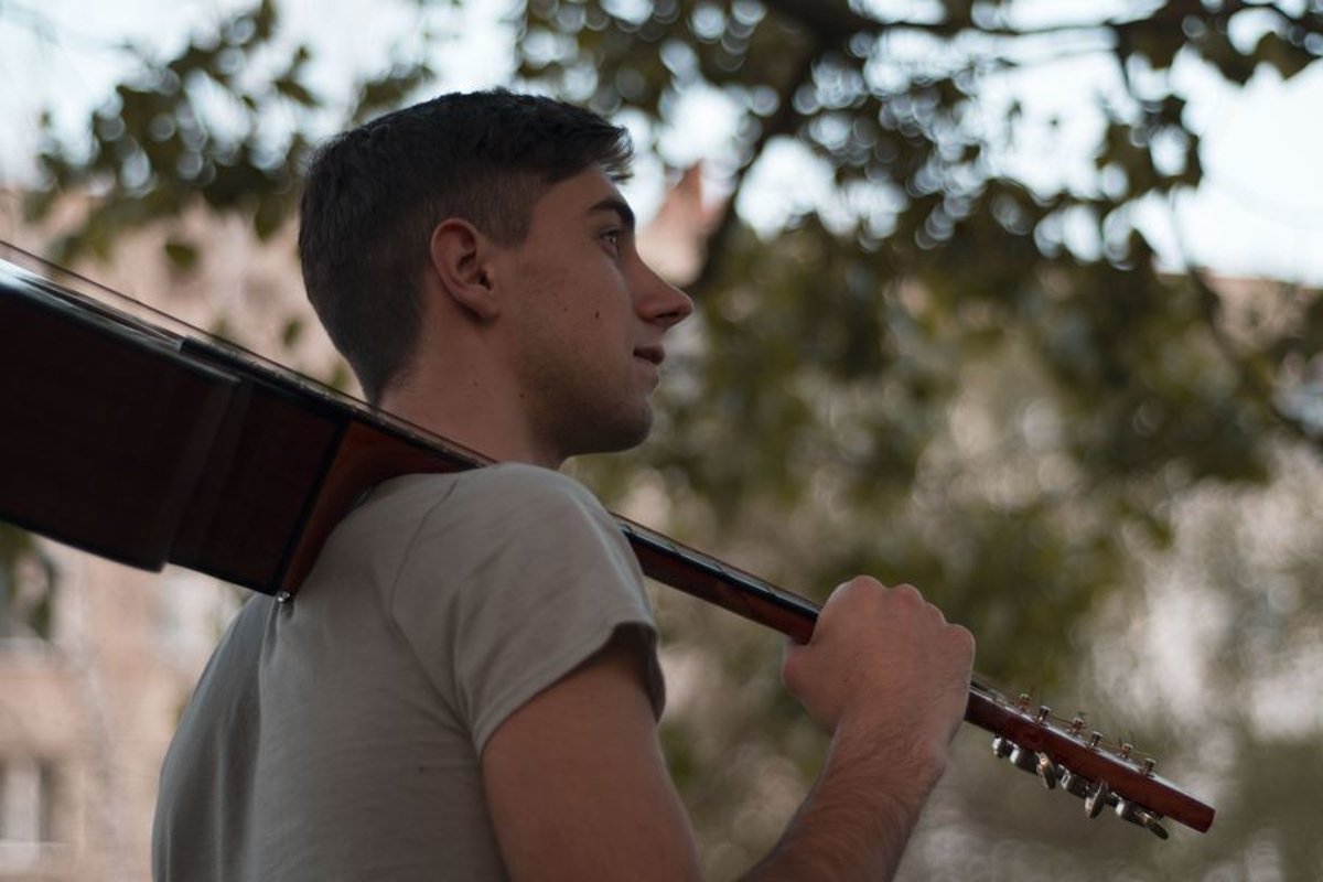 Man plays on acoustic guitar in a park example image 1