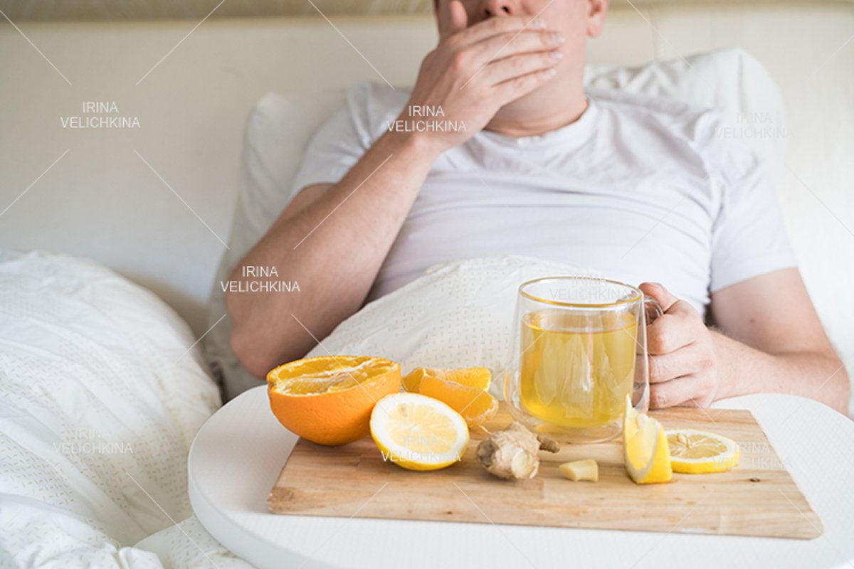 Sick man in bed. Cup of flu drugs. Tea, orange,lemon,ginger example image 1