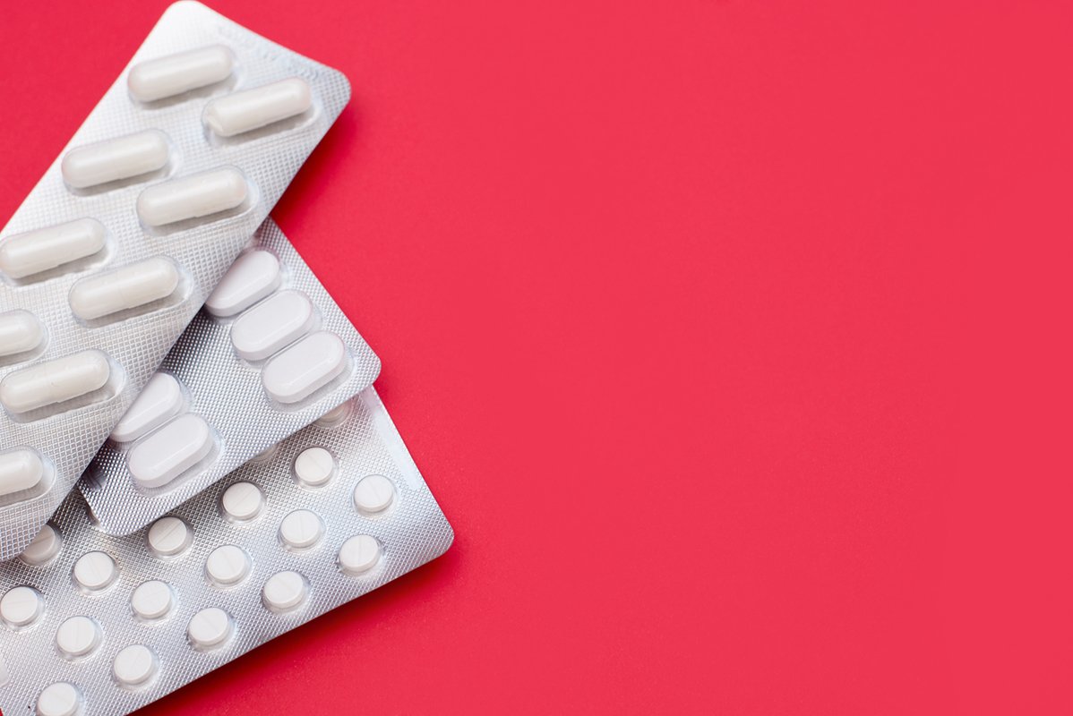 White pills in blister packs lie on a red background example image 1