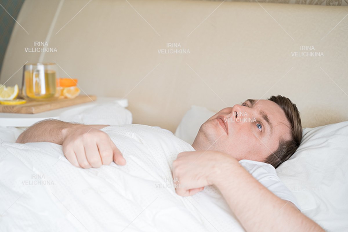 Sick man in bed. Cup of flu drugs. Tea, orange,lemon,ginger example image 1
