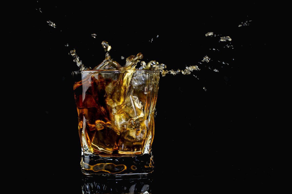 splash alcohol drink whiskey with ice with drops in a glass example image 1