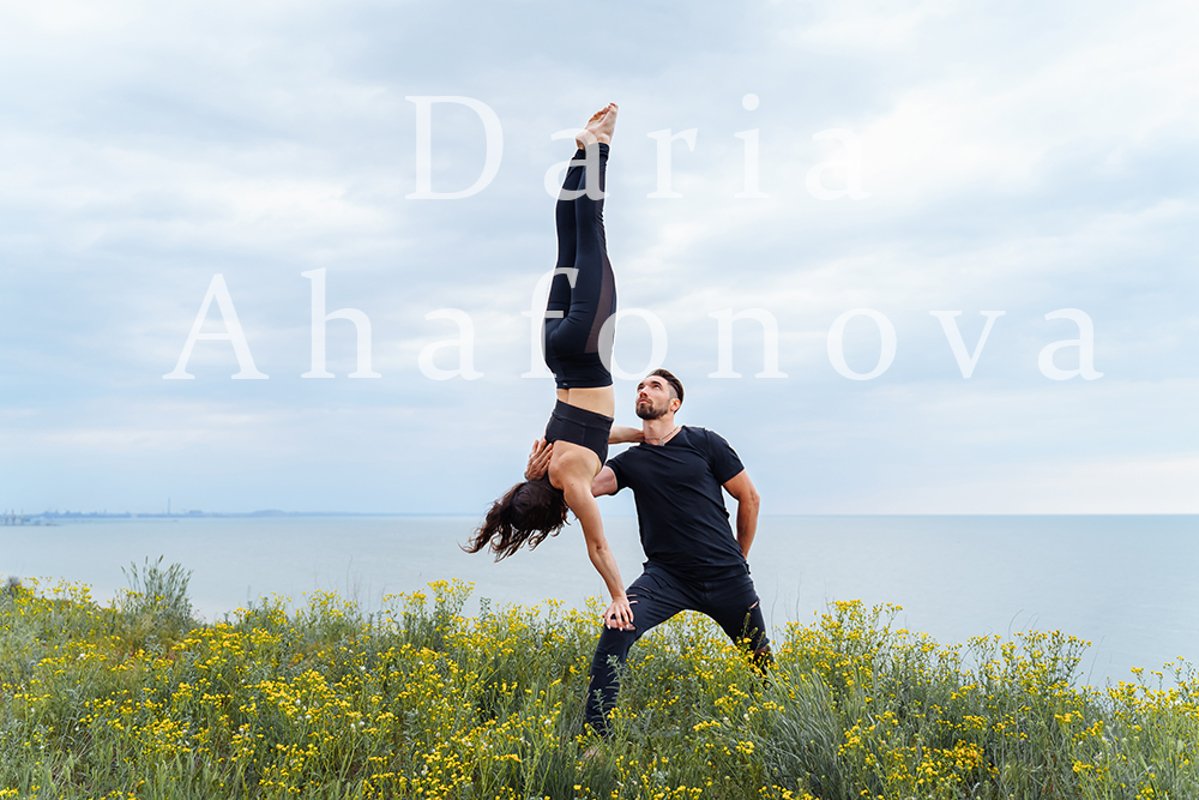 Couple practicing acro yoga poses outdoors outside. example image 1