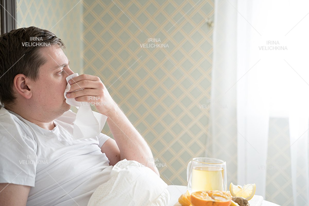 Sick man in bed. Cup of flu drugs. Tea, orange,lemon,ginger example image 1