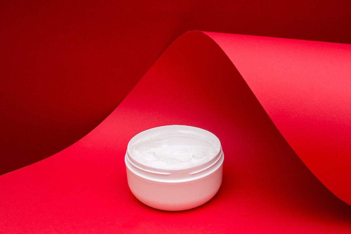 jar of beauty cream on red wave paper background example image 1