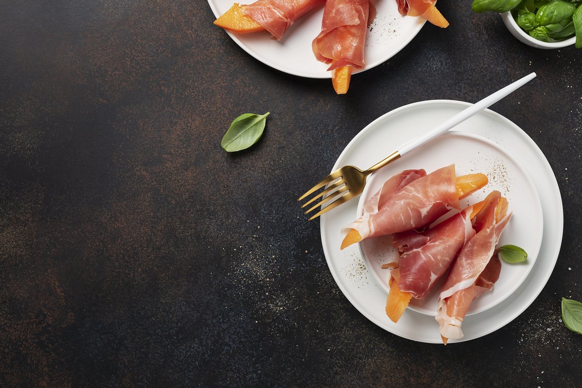 Summer appetizer with sweet melon and ham on dark background example image 1
