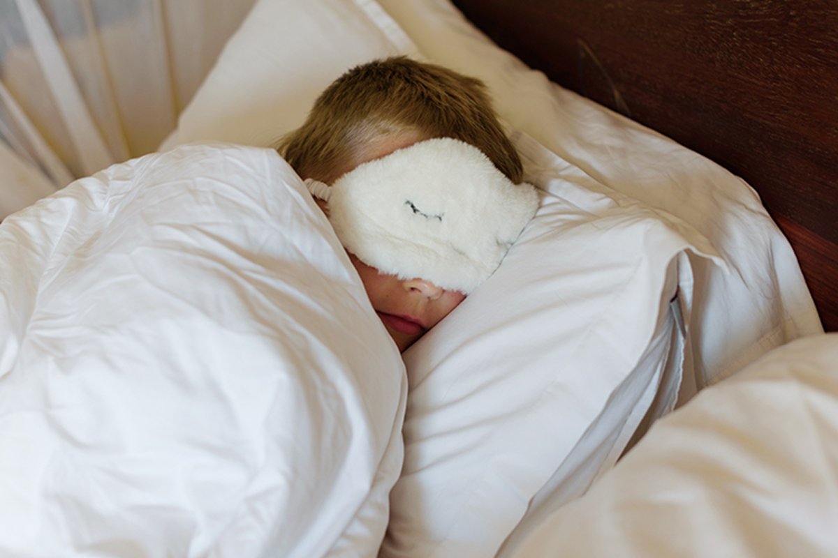 little boy in a sleep mask sleeps in a bed example image 1