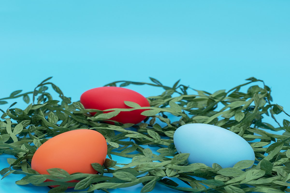 Easter eggs lie on the green leaves on blue background example image 1