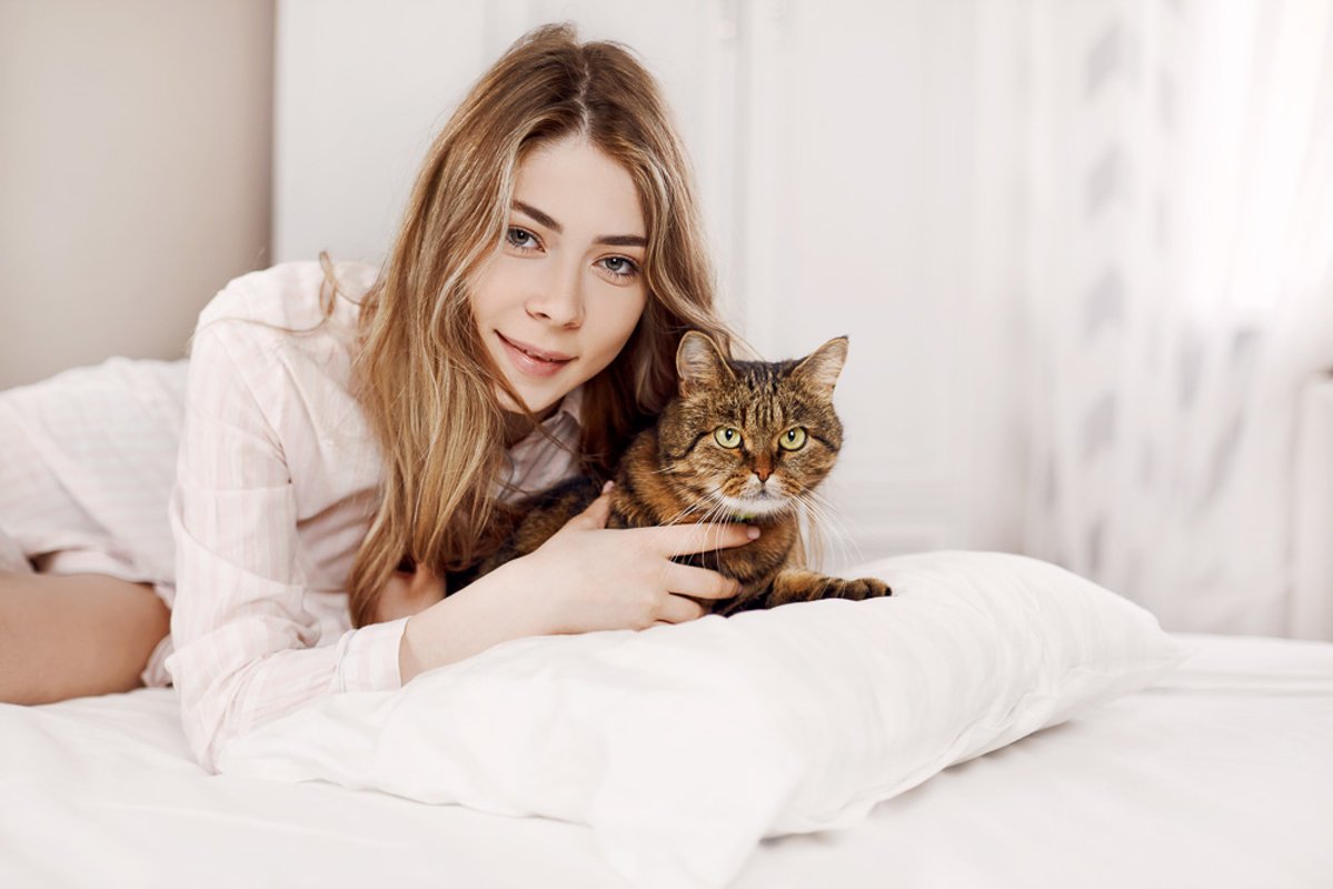 Cute young girl is lying with her cat on the bed at home. example image 1