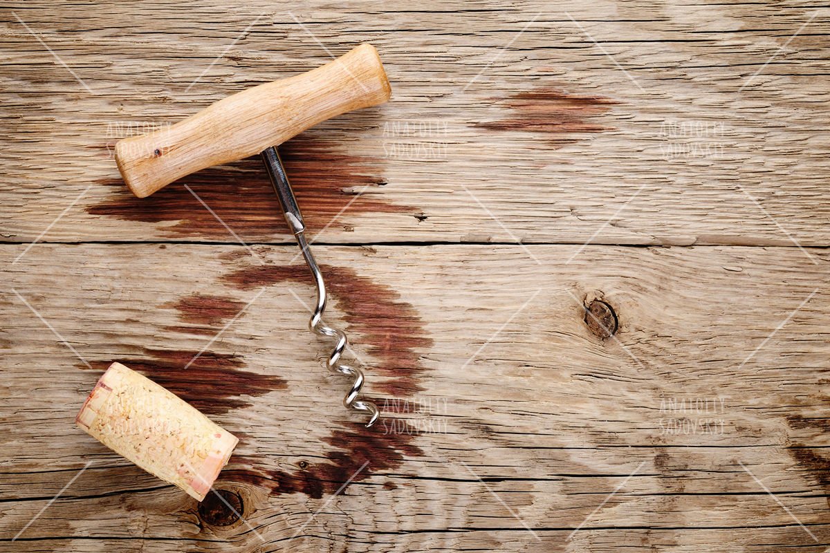 Corkscrew, cork and wine stains on wooden background example image 1
