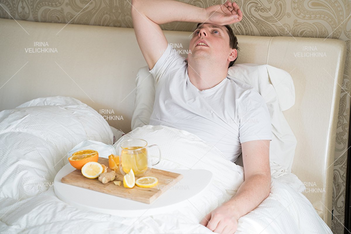 Sick man in bed. Cup of flu drugs. Tea, orange,lemon,ginger example image 1