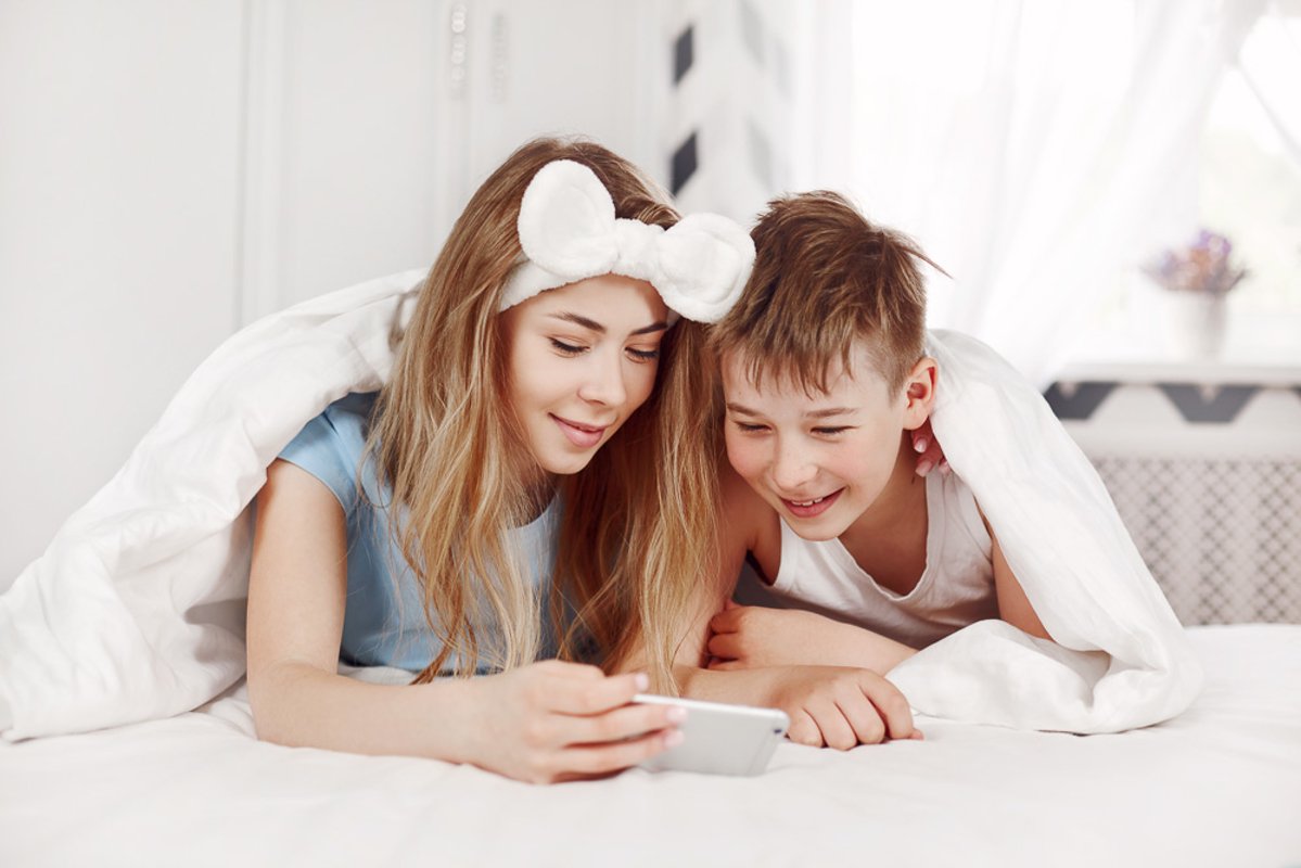The girl and her younger brother look at photos on the phone example image 1