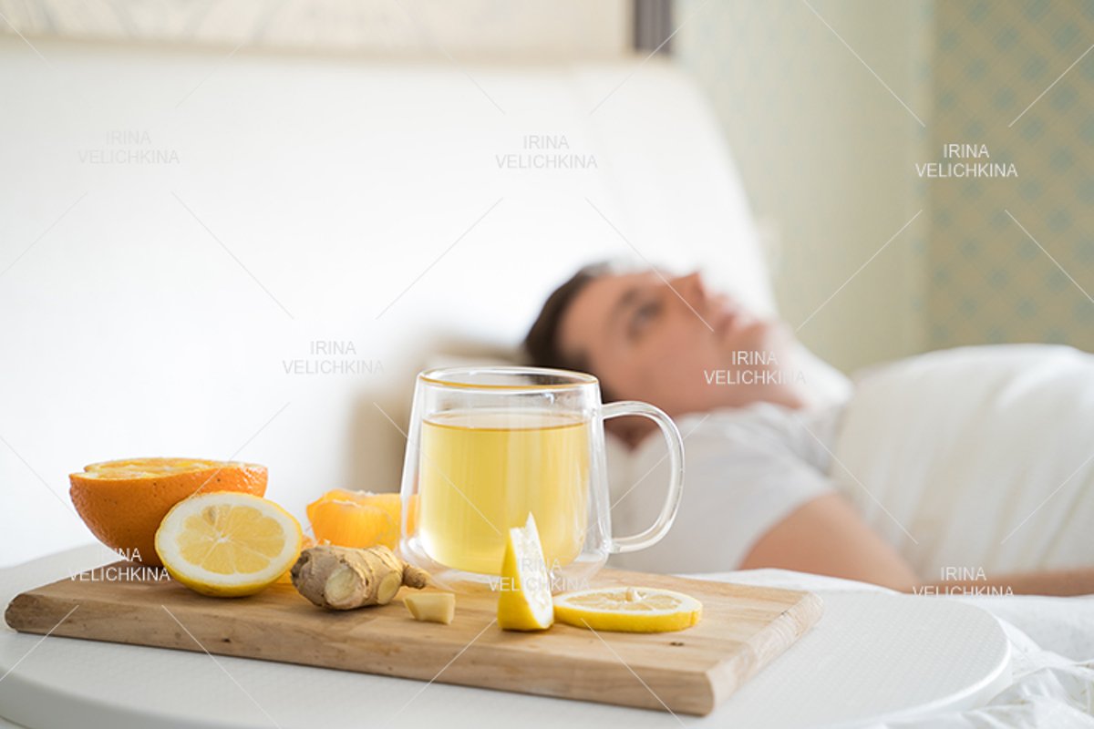 Sick man in bed. Cup of flu drugs. Tea, orange,lemon,ginger example image 1