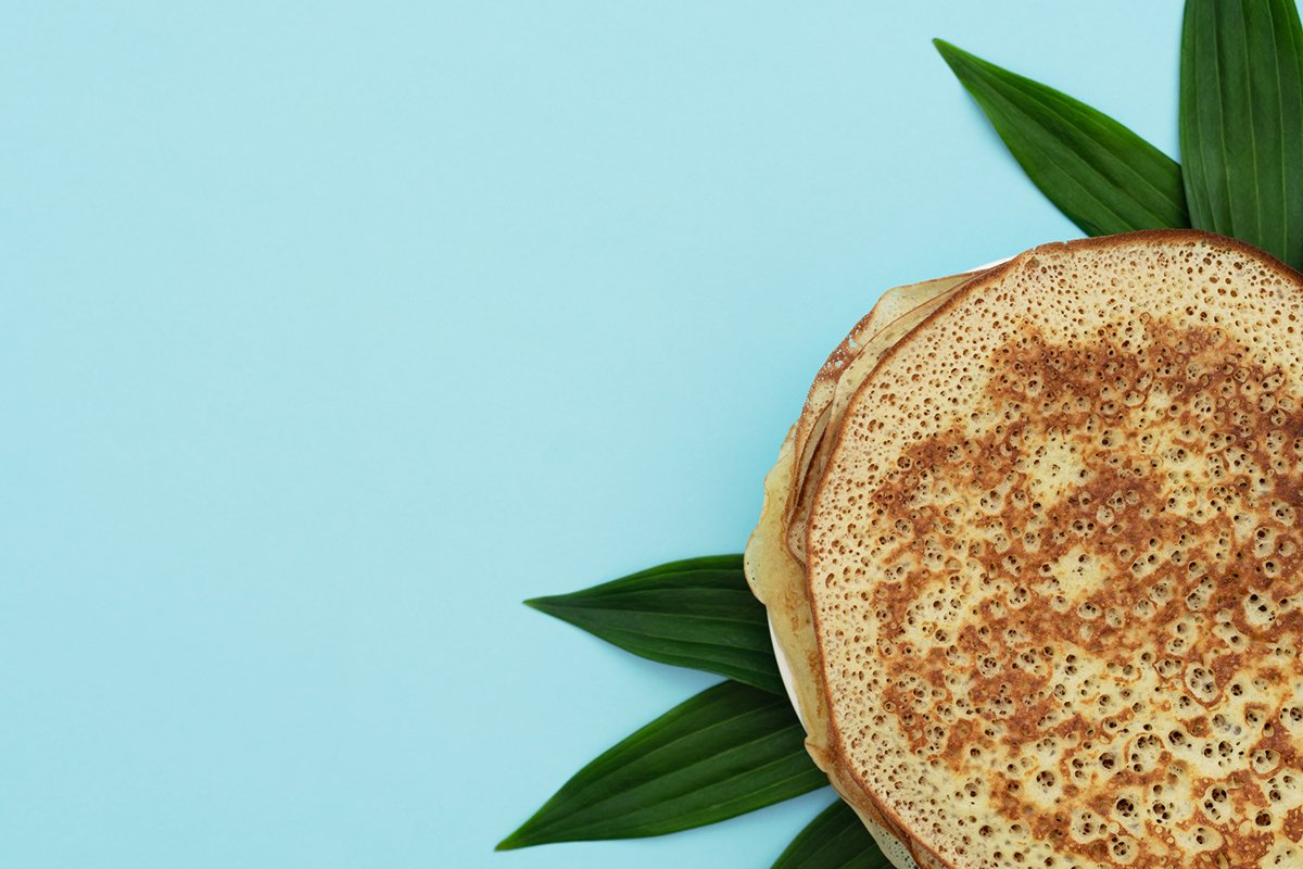 Homemade pancakes on blue background with green leaves example image 1